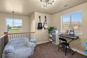 Office space featuring a chandelier, dark colored carpet, a textured ceiling, and plenty of natural light