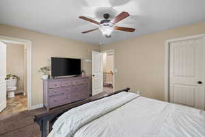 Carpeted bedroom with ceiling fan and ensuite bathroom