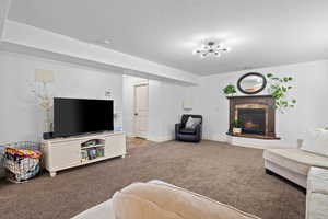 Carpeted living room with a premium fireplace, a textured ceiling, and a chandelier