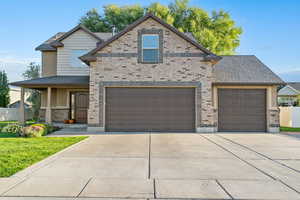 View of front facade featuring concrete driveway, brick siding, covered porch, and an attached garage
