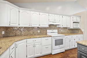 Kitchen with white cabinets, white appliances, tasteful backsplash, light stone counters, and under cabinet range hood