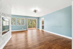 Unfurnished living room featuring wood finished floors and a large fireplace