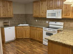 Mother-in-law Kitchen featuring white appliances, light stone countertops, a textured ceiling, dark wood-style flooring, and decorative light fixtures