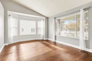 Unfurnished room featuring vaulted ceiling and hardwood / wood-style flooring