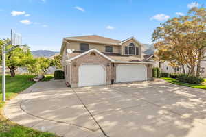 Traditional-style home with a mountain view, concrete driveway, brick siding, and a front lawn