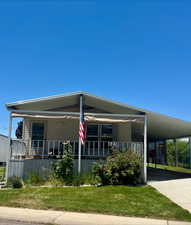 View of front of property featuring an attached carport, driveway, a front lawn, and a porch