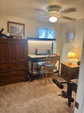 Home office with a textured ceiling, light carpet, and a ceiling fan
