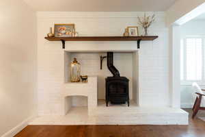 Detailed view of a wood stove, wood finished floors, and brick wall