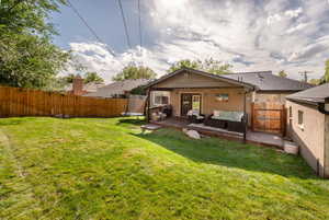 Rear view of property with a trampoline, outdoor lounge area, a fenced backyard, a deck, and stucco siding