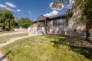View of front of home with an outdoor structure, a front yard, brick siding, a chimney, and concrete driveway