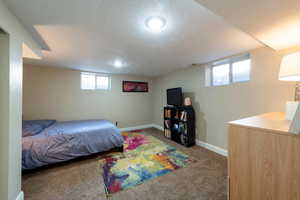 Carpeted bedroom featuring baseboards and a textured ceiling