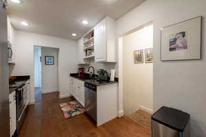 Kitchen featuring white cabinetry, stainless steel appliances, dark wood-style floors, open shelves, and a textured ceiling