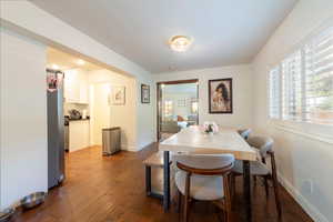 Dining area with dark wood-style floors and baseboards