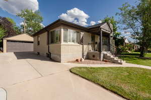 View of front facade with brick siding, a front yard, an outdoor structure, and a garage
