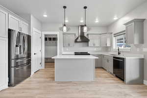 Kitchen featuring gray cabinets, a kitchen island, stainless steel fridge with ice dispenser, pendant lighting, and light wood-style flooring