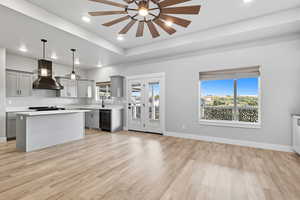 Kitchen featuring gray cabinets, light countertops, decorative light fixtures, a center island, and plenty of natural light