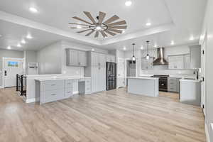 Kitchen featuring gray cabinets, a tray ceiling, light countertops, appliances with stainless steel finishes, and light wood-style floors