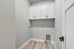 Laundry area with light wood-type flooring, washer hookup, and cabinet space