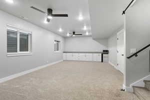 Unfurnished room with stairs, light carpet, and ceiling fan