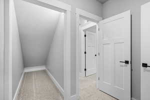 Corridor featuring light colored carpet and baseboards