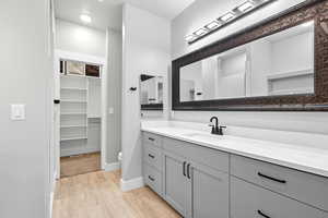 Full bath with light wood-style flooring, vanity, and a spacious closet