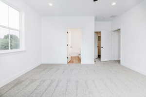 Unfurnished bedroom with light carpet, recessed lighting, connected bathroom, and ceiling fan