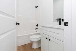 Full bath with vanity, light wood-type flooring, and shower / tub combination
