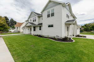 View of side of property featuring a garage, concrete driveway, and a yard