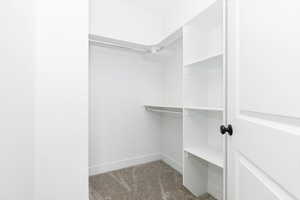 Walk in closet featuring light colored carpet