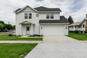 View of front of property featuring driveway, roof with shingles, a front lawn, and an attached garage