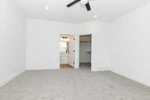 Unfurnished bedroom featuring a spacious closet, light carpet, recessed lighting, ceiling fan, and ensuite bathroom