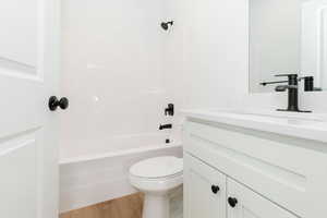Full bath with  shower combination, vanity, and light wood-style floors