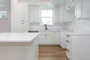Kitchen with white cabinetry, light wood-type flooring, and light stone countertops