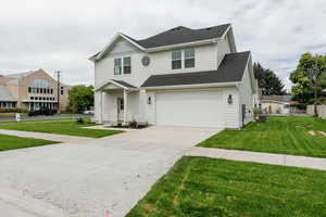View of front facade with a front yard, driveway, a garage, and roof with shingles