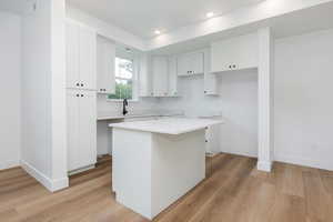 Kitchen with white cabinetry, light wood-style floors, a kitchen island, and recessed lighting