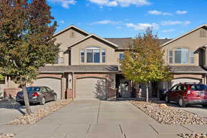 Traditional-style home featuring driveway, brick siding, an attached garage, and stucco siding
