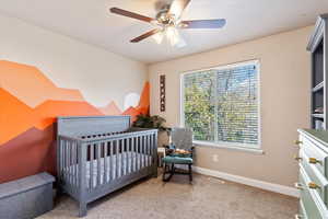 Bedroom with a nursery area, light carpet, and a ceiling fan