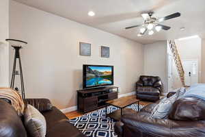 Living area with wood finished floors, stairs, ceiling fan, and recessed lighting