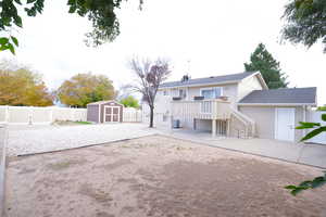 Back of house featuring a patio area, a shed, a fenced backyard, and a deck