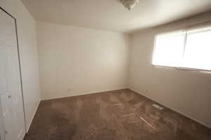 Spare room with dark carpet and baseboards