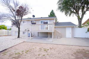 Back of property with a wooden deck, a patio, and roof with shingles