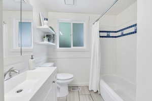 Bathroom featuring vanity, shower / tub combo, and a wainscoted wall