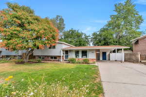 Tri-level home featuring brick siding, driveway, and a carport