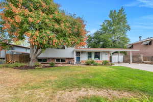Tri-level home with an attached carport, brick siding, and concrete driveway