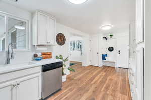 Kitchen with white cabinetry, dishwasher, and light wood-type flooring