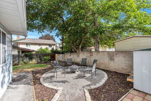 Fenced backyard featuring a patio, a fire pit, and an outdoor structure