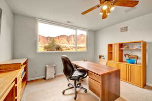 Office area with light carpet, a mountain view, and ceiling fan