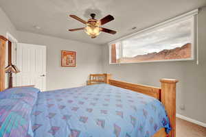 Carpeted bedroom with ceiling fan and baseboards