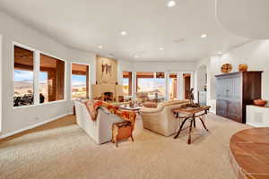 Living room with recessed lighting, light carpet, arched walkways, and a fireplace