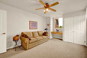 Carpeted living room featuring baseboards and ceiling fan